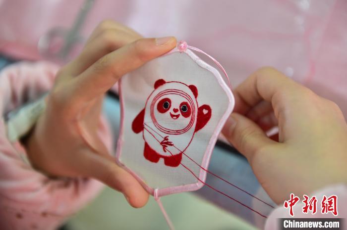 圖為一名小學生正在繡制2022年北京冬奧會吉祥物“冰墩墩”形象?！∮髟屏?攝