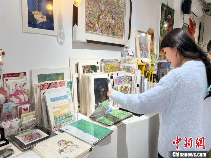 圖為藝術(shù)品商店內(nèi)，顧客挑選插畫作品?！＄婌?攝