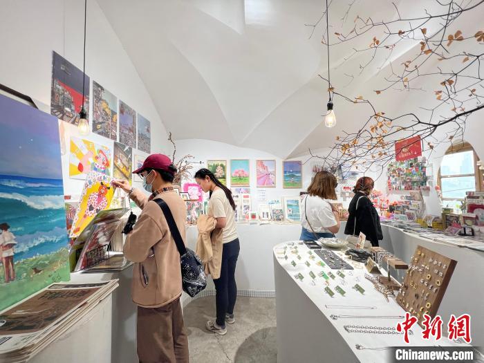 圖為藝術(shù)品商店內(nèi)，顧客挑選插畫作品?！＄婌?攝