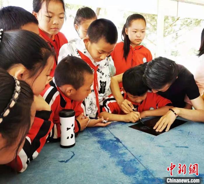 圖為朱增平(右一)教學(xué)生創(chuàng)作鍥金畫。(資料圖) 受訪者供圖