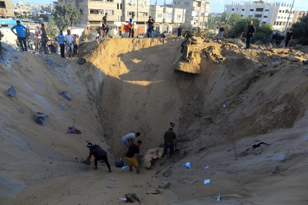 10月16日，在加沙地帶南部城市汗尤尼斯，人們?cè)谠庖陨幸u擊后的建筑廢墟中救援傷者。 新華社發(fā)（亞西爾·庫(kù)迪 攝）