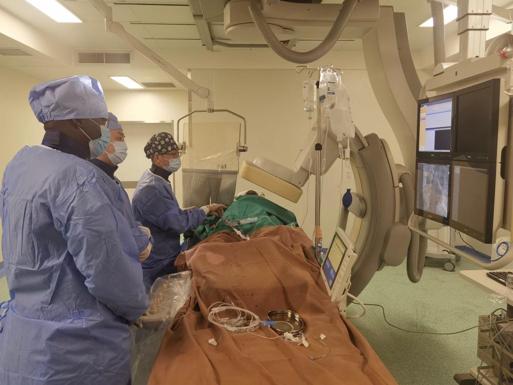 中國第29批援幾內亞醫(yī)療隊隊員、首都醫(yī)科大學附屬北京天壇醫(yī)院心內科副主任醫(yī)師王汝朋（右一）正在給患者做手術。（北京天壇醫(yī)院供圖）