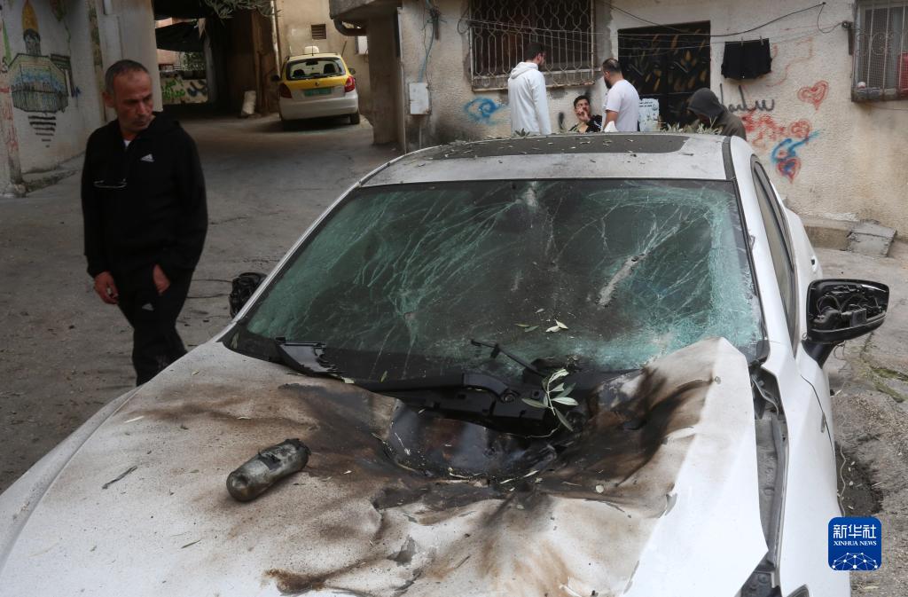 12月17日，在約旦河西岸城市圖勒凱爾姆附近的一處難民營，人們查看在沖突中損毀的車輛。新華社發(fā)（尼達爾·艾仕塔耶?dāng)z）