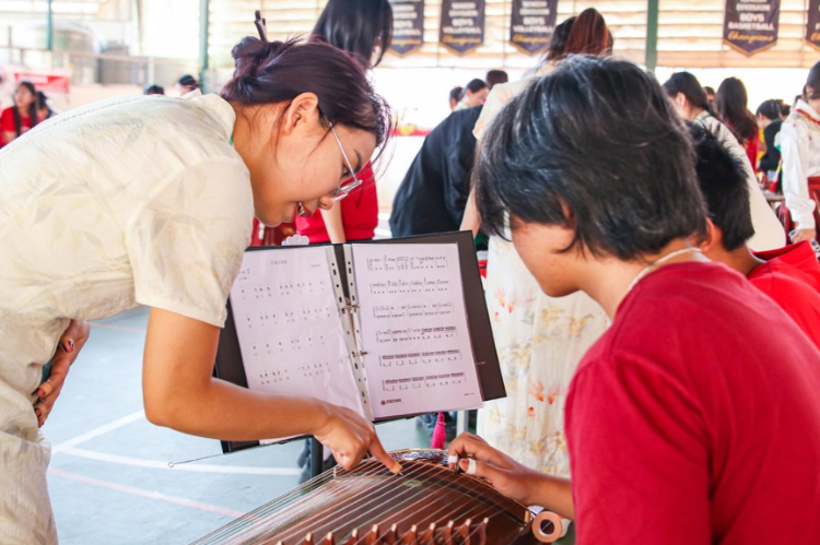 志愿者教師指導(dǎo)學(xué)生彈奏古箏?；顒又鬓k方供圖