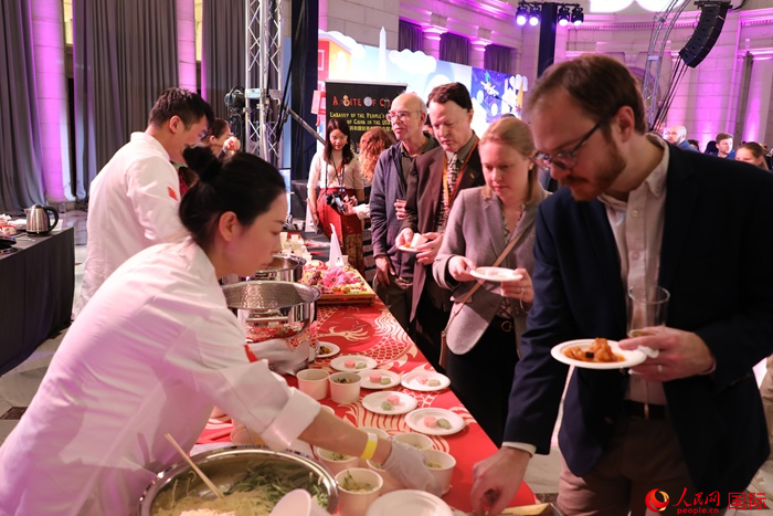 當?shù)貢r間3月7日晚，華盛頓聯(lián)合車站廣場舉行駐美使團“使館主廚挑戰(zhàn)賽”。圖為當?shù)孛癖娫谥袊古_前體驗中國美食。人民網(wǎng)記者 李志偉攝