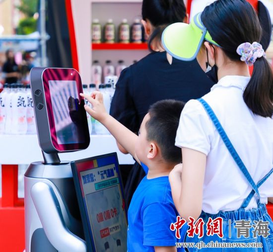 圖為一名小朋友正在和機器人“志愿者”進行互動。 沐聞 攝