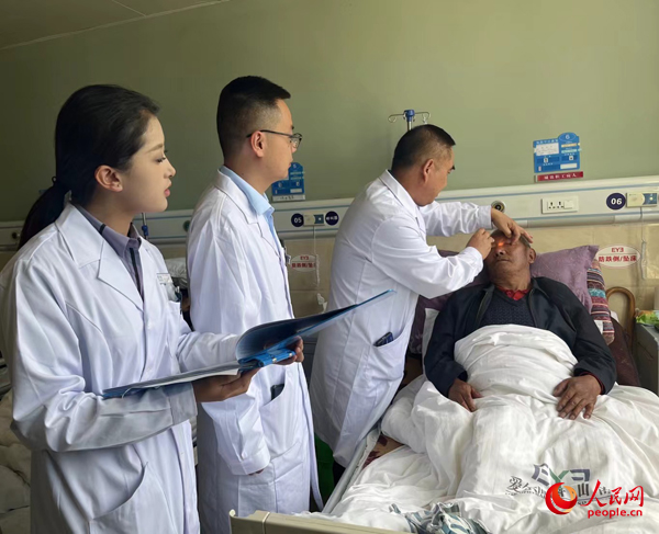 董光明（左三）帶領(lǐng)醫(yī)生對患者進行術(shù)前檢查。人民網(wǎng)記者 杜燕飛攝