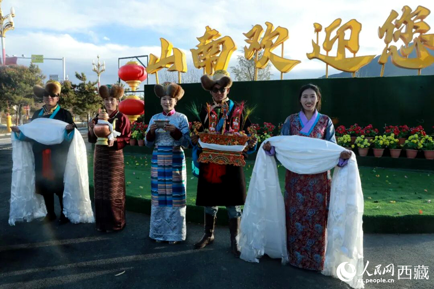 扎西曲登社區(qū)的居民在“山南歡迎您”標(biāo)志前，手持潔白哈達(dá)和切瑪，列隊(duì)迎接來(lái)自區(qū)內(nèi)外的游客，用最隆重的禮儀開(kāi)啟一場(chǎng)沉浸式藏歷新年民俗體驗(yàn)之旅。人民網(wǎng)記者 吳雨仁攝
