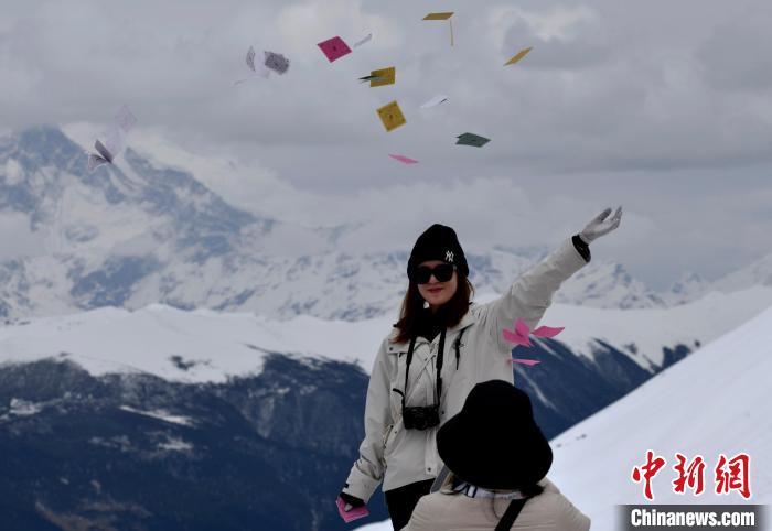 圖為5月14日，游客在西藏林芝色季拉山觀景臺(tái)拋灑“隆達(dá)”(風(fēng)馬旗，藏族民眾的一種祈福方式)?！±盍?攝