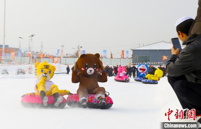 圖為臨夏市南龍鎮(zhèn)馬家莊村舉辦的鄉(xiāng)村文化旅游節(jié)上，游客穿著卡通服裝在體驗(yàn)雪上飛碟項(xiàng)目。近年來(lái)，臨夏州形成了“春賞花、夏避暑、秋摘果、冬玩雪”的全季節(jié)旅游產(chǎn)品體系。(資料圖) 高展 攝