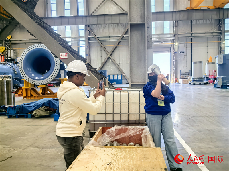 外媒記者掂量廠房內(nèi)的巨型螺栓。人民網(wǎng) 楊春燕攝