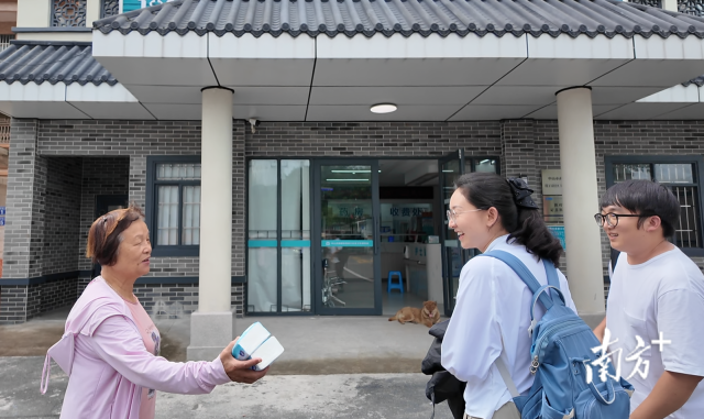 公共服務(wù)組成員王櫻潔（中）和張龍（右）在崖口村衛(wèi)生室前跟村民打招呼。