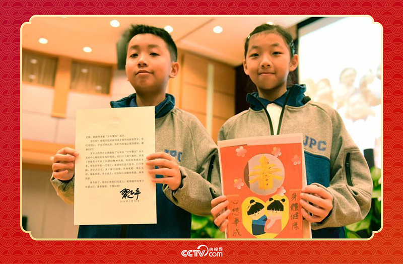 圖為香港“少年警訊”成員郭宏晞（左）展示習(xí)主席回信、羅顥凝（右）展示送給習(xí)主席的賀卡并合影。