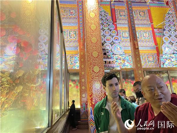 7月25日，省級(jí)非物質(zhì)文化遺產(chǎn)項(xiàng)目塔爾寺酥油花的代表性傳承人朋措堅(jiān)參（右）在塔爾寺酥油花館講解酥油花的制作過程。人民網(wǎng) 謝瑩攝