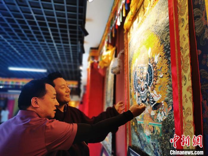 圖為久美尖措展示唐卡作品?！?zhí)砀?攝