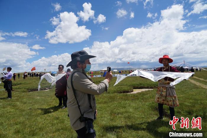 圖為一名外籍?dāng)z影師記錄當(dāng)?shù)夭刈鍤g迎儀式?！●R銘言 攝