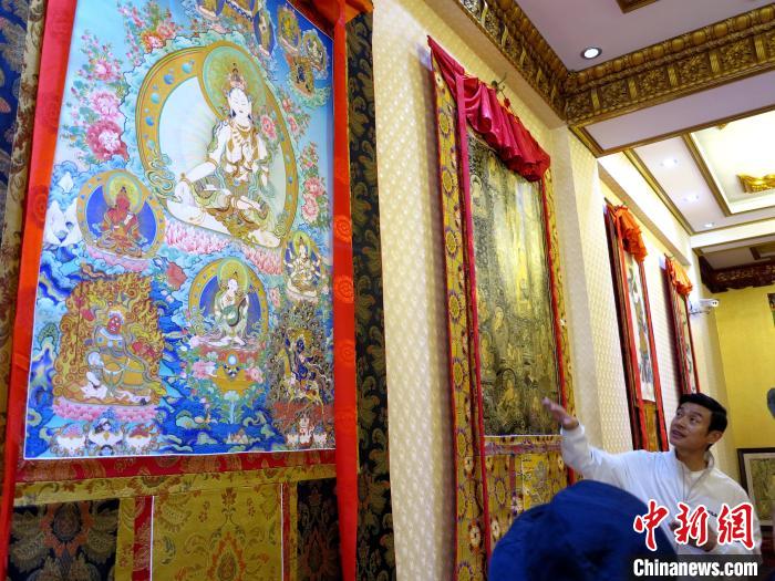 圖為完德尖措展示熱貢龍樹畫苑內(nèi)的唐卡。　張?zhí)砀?攝
