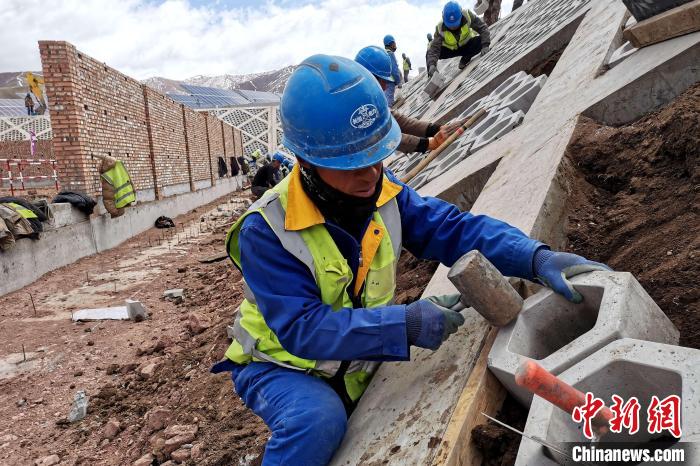 圖為光伏發(fā)電項目施工區(qū)工人在護坡鋪設空心磚?！±铍h 攝