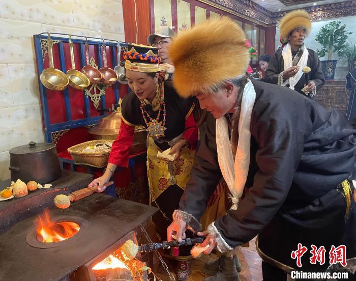 圖為人們在火上烤節(jié)日美食“結(jié)達(dá)”?！∪轿木?攝