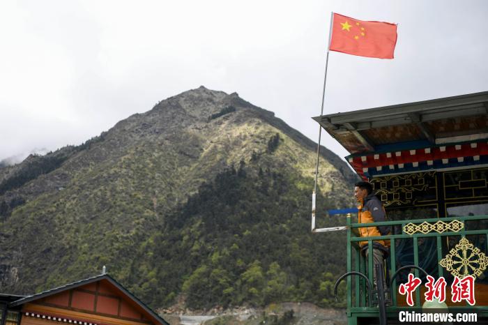 村民站在樓房上觀望?！钊A峰 攝