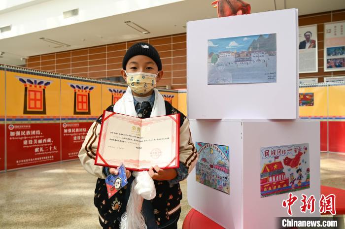 圖為一名獲獎(jiǎng)學(xué)生與自己的繪畫作品合影?！≮w朗 攝