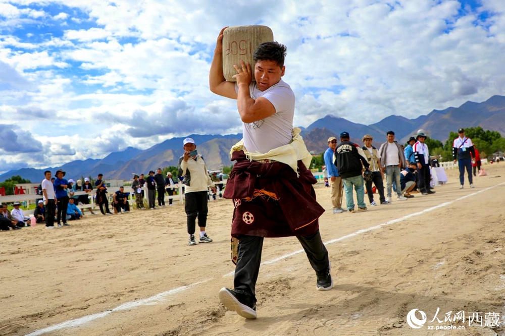 來自拉薩市當(dāng)雄縣的牧民選手將一塊150斤重的石頭扛在肩上飛奔。