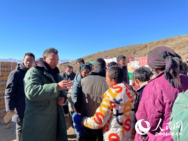 定日縣公安局干警頓珠次仁（左二）正在協(xié)助分發(fā)物資。人民網記者 郝潔攝