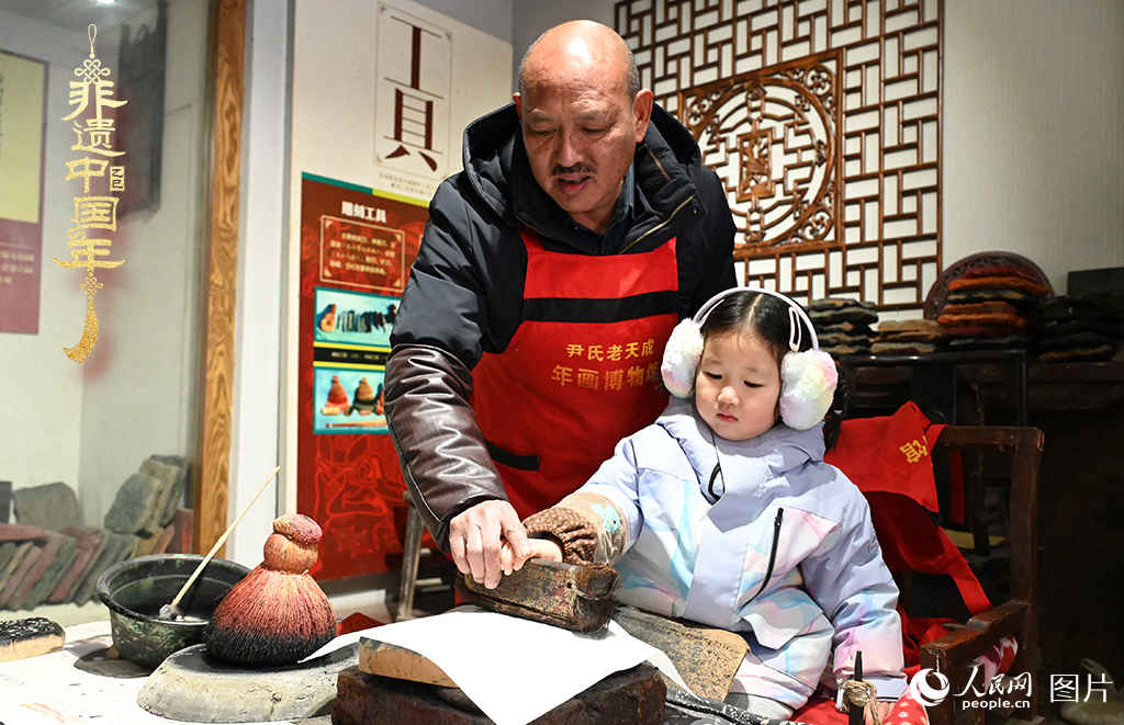 2025年1月27日，河南開封朱仙鎮(zhèn)木版年畫藝人尹國法指導小朋友研習年畫印制技藝。朱仙鎮(zhèn)木版年畫源自漢唐壁畫藝術，是中國木版年畫的鼻祖。2006年5月20日，朱仙鎮(zhèn)木版年畫經(jīng)國務院批準列入第一批國家級非物質(zhì)文化遺產(chǎn)名錄。人民網(wǎng)記者 王玉興攝
