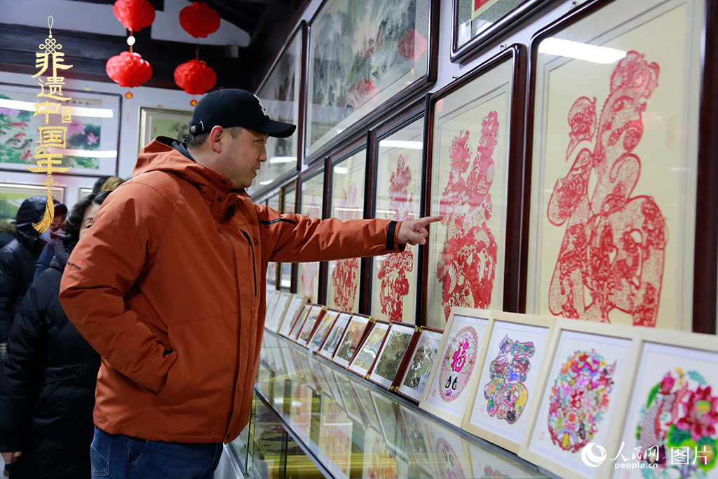 2025年1月23日，游客在天津楊柳青古鎮(zhèn)欣賞傳統(tǒng)剪紙作品，感受指尖上的古老藝術。人民網(wǎng)記者 崔新耀攝