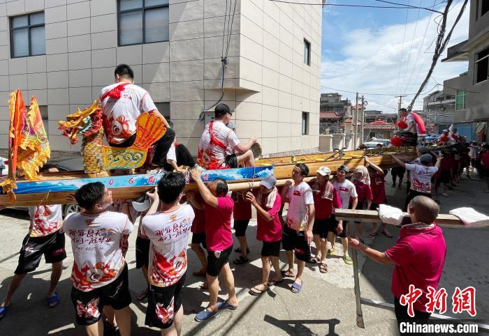 圖為5月29日，長(zhǎng)樂江田鎮(zhèn)村民們肩扛著新龍舟舉行入水前游街儀式。　張斌 攝