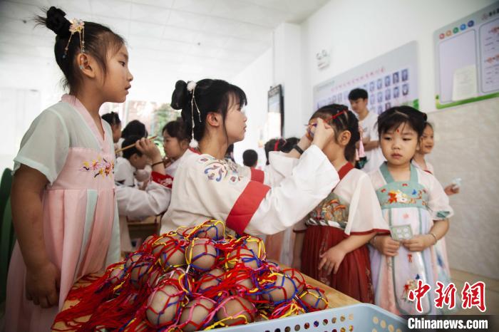 圖為幼兒園的老師們穿上漢服為小朋友們戴上彩蛋，寓意著幸福安康?！《^生 攝